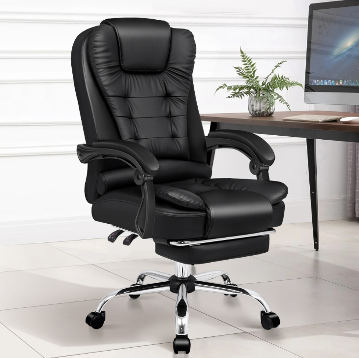 Black leather executive office chair with armrests, footrest, and adjustable height settings, positioned in an office setting.